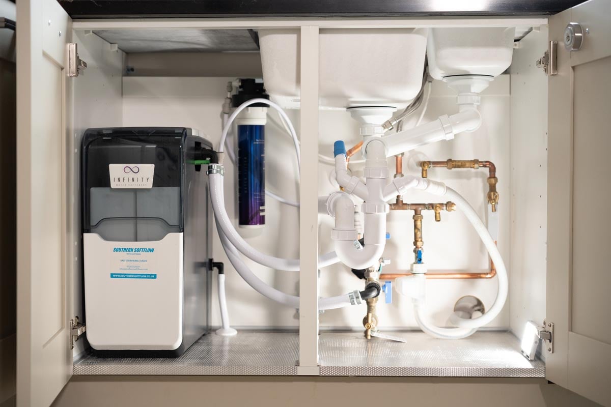 Infinity water softener and water filter system installed neatly inside a kitchen cupboard